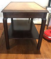 Front view of rectangular wooden side table with lighter finish top and dark lower shelf, visible leg design