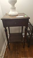 Full view of vintage side table with lamp on top showing overall form and condition.