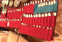 Wide view of the flatware pieces laid out on table with protective red pouches, showing forks, spoons, knives organized in rows.