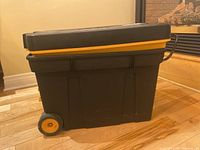 Closed black and yellow plastic mobile tool chest on wheels showing side profile.