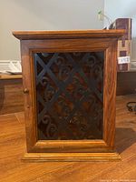 Front view of the wood key cabinet showing decorative metal scrollwork on the door and wooden knob.