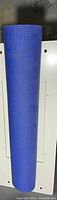 Photo of a single blue yoga mat rolled up showing its textured surface.