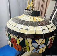 Side view showing the dome top with cream and brown panes transitioning to colorful floral and butterfly pattern on the bottom rim.