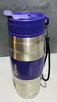 Photo of Bubba thermal mug, showing the purple plastic lid, stainless steel body, purple band with Bubba logo, and attached black strap.