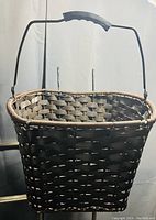 Photo of a rectangular woven basket with a handle, showing the basket's weave pattern and handle grip.