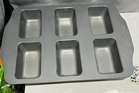 Photo of a rectangular metal mini loaf bakeware with six short loaf cavities, in good condition with no visible damage.