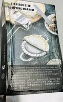 Photo of box packaging for stainless steel dumpling machine showing product image and usage instructions in English and Chinese.