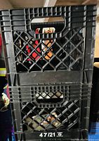 Stacked view of two black plastic milk crates with lattice sides and handles
