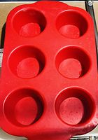 Photo of one red silicone muffin tin with six round cups for baking muffins