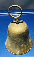 Photo of a solid vintage brass bell showing its overall shape, top loop handle with screw, and decorative beaded edge at bottom rim.