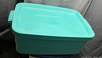 Photo of teal rectangular plastic storage tote with lid and side handles, showing overall condition.