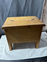 Photo showing the closed vintage wooden shoe shining box from the front side on a soft cloth.