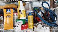 Photo shows assorted car supplies including blue jumper cables, bottles, sponges, and a yellow box labeled Belden spark plug wire set.
