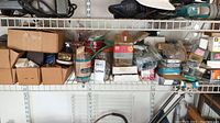 Wide view of shelf containing multiple boxes and containers filled with various fasteners including nails, screws, and bolts.