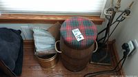 Overall lot showing barrel stool with plaid cushion, brass bucket, firestart sticks in bag, and fireplace tools.