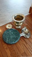 Green marble lazy Susan with silver-tone champagne bucket, gravy boat, and small dish displayed on wooden floor.