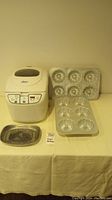 Oster bread maker with control panel, metal trays on both sides on table