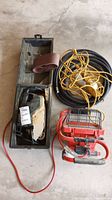 Photo showing Craftsman power sander in case, sanding belt, red work light and yellow extension cord coiled.