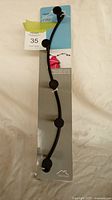 Front view of packaged black curved five-peg metal coat rack