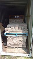 Four pallets of stacked rectangular pavers inside storage container