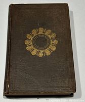 Dark brown cloth hardcover exterior with blind embossing and gold-stamped medallion