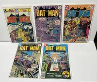 Five Batman comic books displayed in protective sleeves on a white surface, showing front covers, colorful and vintage style.