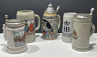 Front view showing all five beer steins in a row, highlighting differing designs and presence of lids.