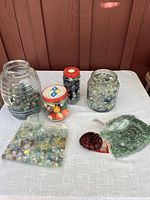 Photo showing three glass jars, a bag of multicolored glass marbles, and two small plastic bags of glass pieces.