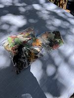 Three tightly sealed plastic bags filled with various animal figurine toys placed on a fabric surface with shadows from nearby trees.