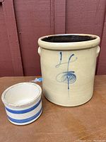 Photo showing two antique crocks, one large beige with blue decoration and one smaller with blue stripes.