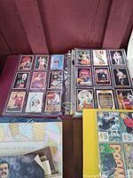 Photo of open binder showing two pages of Coca-Cola collectible cards featuring vintage advertisements and images.