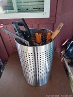 Cylinder container filled with various hand tools including saws, pliers, and a metal grater.