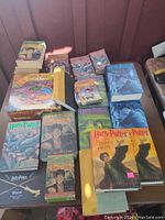 Top-view photo of multiple Harry Potter books including paperbacks and hardcovers, with colorful cover illustrations and boxed collectibles.