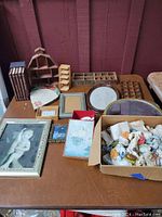 Photo of various small animal figurines, multiple wooden shadowbox display shelves with compartments, framed art and mirror, and a photo album on wood table.