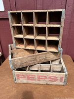 Full view of three stacked vintage Pepsi wooden crates showing multiple bottle slots and visible wear including scratches and rough edges.