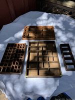 Four wooden trays on a white cloth-covered table seen from above, showing varied compartments in each tray.