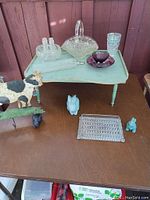 Lap tray shown closed with multiple decorative items on top including glassware, ceramics, and a wooden cow figurine.