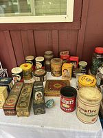 Overview of various collectible tins placed on a table outside, showing brands and packaging styles.
