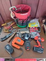 Top view of assorted tools on a table, showing a red Husky tool organizer, cordless drill, jigsaw, saw blades, pliers, and other tools.