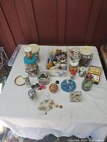 Overall view of various jars and containers filled with buttons, spread on white cloth