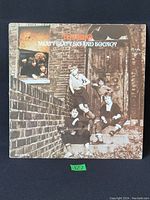 Front cover of The Who Meaty Beaty Big and Bouncy vinyl record sleeve showing band members arranged on brick steps and window.