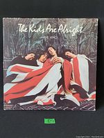 Front cover of 'The Kids Are Alright' vinyl LP by The Who showing four band members wrapped in a red and white flag.