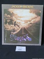 Front cover of the Jackson Browne vinyl LP 'Running on Empty' showing artwork with road and drum set under cloudy sky.