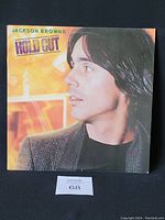 Front cover of Jackson Browne Hold Out album showing portrait of artist with warm background.