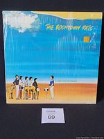 Front cover of The Boomtown Rats 'A Tonic for the Troops' vinyl LP, showing the band members standing in a desert setting under a blue sky with clouds, partially shrink-wrapped sleeve.