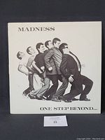 Front cover of Madness vinyl LP 'One Step Beyond...' showing band members in black and white photo leaning backwards.