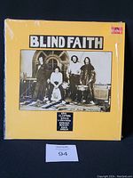 Front cover of Blind Faith vinyl LP album with yellow background and band photo.