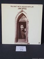 Front cover of Jim Croce's album 'You Don't Mess Around with Jim' showing Jim Croce peeking through an arch on a white background.