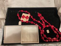 Photo showing cherry red bead necklaces and earrings on black velvet with old Eaton's branded white box beside.