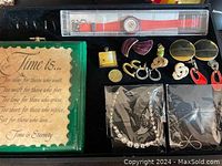 Assorted jewelry including earrings, pendants, rhinestone costume pieces, and 1986 Swatch watch new in box with red band, plus rare initialed coin visible.